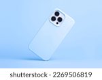 iPhone 14 and 13 Pro Max in light blue soft silicone case falls down back view, phone cover mockup in monochrome colours isolated on blue background