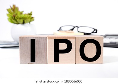 IPO, text on wood blocks on white background near glasses and plants
