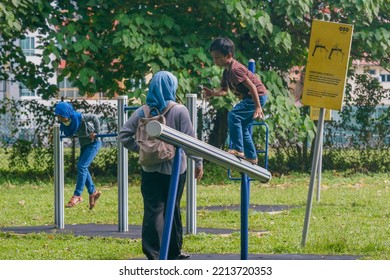 IPOH, MALAYSIA - October 10, 2022 : A Group Of Elderly People And Children Using Exercise Equipment In The Park On A Sunny Morning.