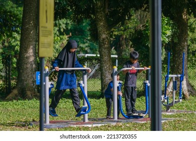 IPOH, MALAYSIA - October 10, 2022 : A Group Of Elderly People And Children Using Exercise Equipment In The Park On A Sunny Morning.