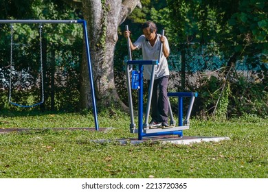 IPOH, MALAYSIA - October 10, 2022 : A Group Of Elderly People And Children Using Exercise Equipment In The Park On A Sunny Morning.