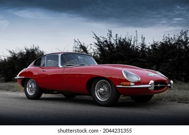Ipswich Suffolk UK - 9 18 2021: Red Jaguar E-type Series 1 on country road and dark sky background