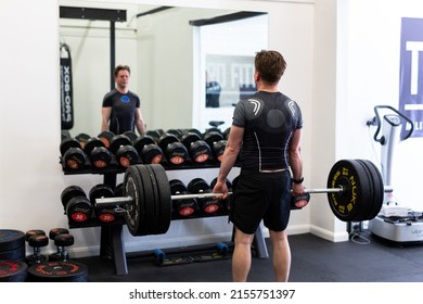 Ipswich Suffolk UK April 03 2022: Young Fit Man Does Dead Lift In Modern Gym. His Looking In The Mirror To Check His Form And Lift