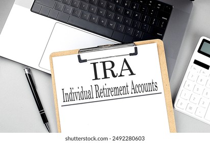 IRA word on clipboard on a laptop with calculator and pen . 