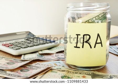 IRA written on a stick and jar with dollars.