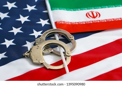 Iranian Flag In Handcuffs On The Background Of The American Flag. US Sanctions Against Iran.