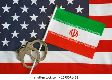 Iranian Flag In Handcuffs On The Background Of The American Flag. US Sanctions Against Iran.