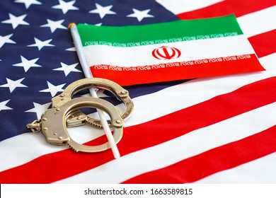 Iranian Flag In Handcuffs On The Background Of The American Flag. US Sanctions Against Iran.