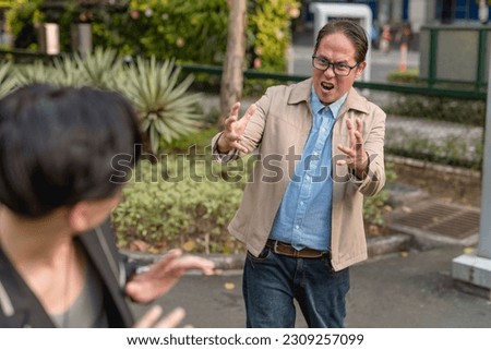 An irate boss scolds and insults a frightened guy in public during a heated argument outside. Stock photo © 