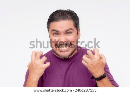 An irate man grinding his teeth, while looking wide eyed at someone and gesturing with his hands. Looking at the camera while brimming in bitter hatred. Isolated on a white background.