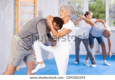 Irate mature female attendee of self-defense classes fighting with her opponent in sports hall