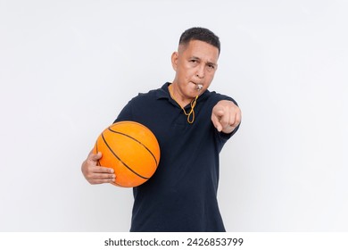 An irate middle-aged basketball coach or referee in casual attire holding a ball blowing a whistle, calling a foul. Isolated on a white background. - Powered by Shutterstock