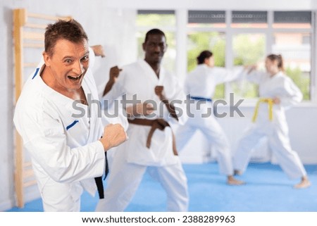 Irate middle-aged male karate practitioner fighting with his opponent in sports hall