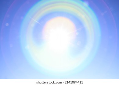 Iridescent circular glare from the bright sun on the blue sky. Beautiful background to illustrate celestial phenomena, aura, high vibrations, the universe 