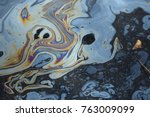 Iridescent colors abstract shapes on tar water surface of natural asphalt pit.