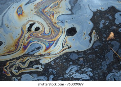Iridescent colors abstract shapes on tar water surface of natural asphalt pit.