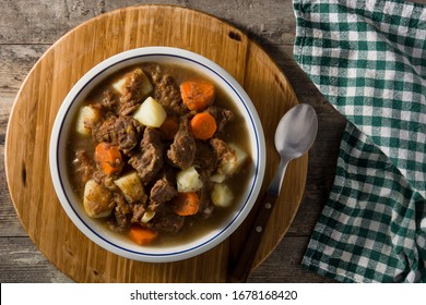 Irish beef stew with carrots and potatoes on wooden table. Top view. Copy space