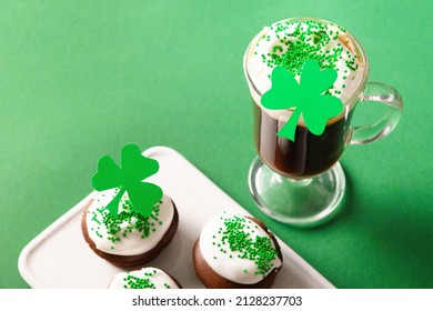 Irish coffee and special cupcakes for Happy St Patricks Day on green background. Close up. Copy space. Festive traditional food.