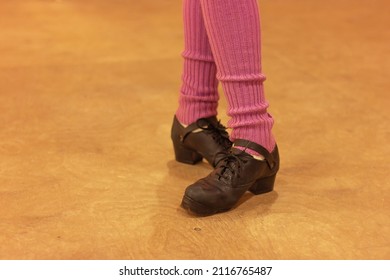 Irish dancer in hard shoes and purple leggings on a wooden floor, legs close up. Irish folk dancing