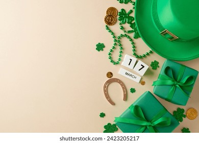 Irish elegance: Stylish gifts for St. Patrick's Day. Top view composition of cube calendar, traditional hat, festive gift boxes, horseshoe, trefoils, coins, beads on beige background with advert space - Powered by Shutterstock