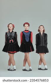 Irish ensemble of three beautiful women in concert costumes and Ghillies Hard Shoes dance together in a row. Full-length studio portrait on a grey background. - Shutterstock ID 2354576853