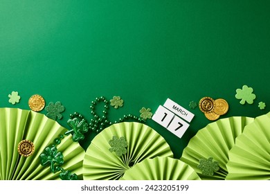 Irish jigs and jollity: St. Patrick's Day merriment. Side view photo of cube calendar, folding fans, trefoils, coins, beads on green background with space for greetings - Powered by Shutterstock