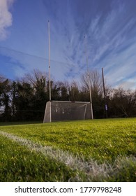 Irish National Sport Goal Posts On A Green Grass Training Pitch. Concept Practice Rugby, Hurling, Camogie, Gaelic Football. Blue Cloudy Sky And Dark Trees Behind Goal Post.