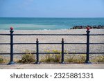 The Irish Sea and pebble beach seen through symmetrical metal railings of the promenade in Bray, Ireland.