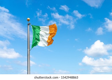 Irish Tricolour Flying In Full Sunshine Against Blue Sky