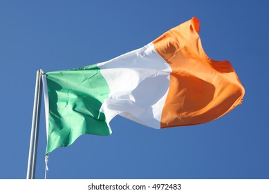 Irish Tricolour Flying In Full Sunshine Against Blue Sky