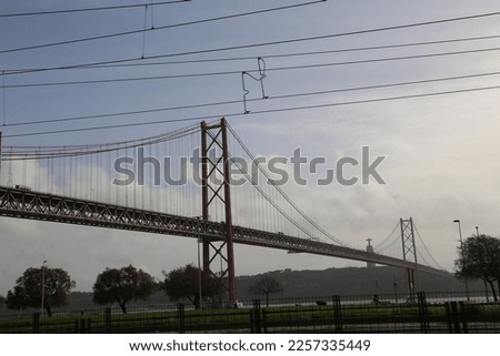 Iron bridge. Suspended road over the river. Cloudy sky. Lisbon, Portugal.