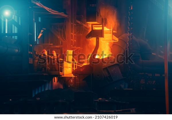 Iron casting in foundry. Metallurgical plant.\
Liquid metal pouring from ladle container into molds in blast\
furnace. Heavy metallurgy\
industry