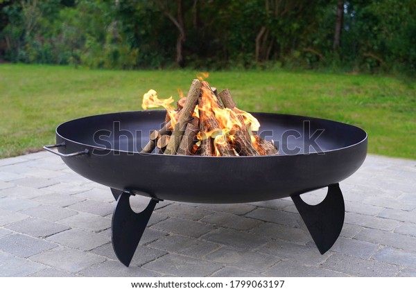 Iron fire pit\
and burning fire in  a garden\
.