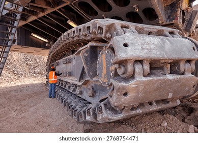 The iron foundation of a mining giant — a dramatic low-angle perspective reveals the massive steel crawler tracks of an electric rope shovel, each individual link forged to carry hundreds of tonnes of machine weight across the unforgiving rocky floor of a large open pit copper mine. This extraordinary close-up captures the raw engineering brilliance, uncompromising build quality, and sheer industrial scale that make the electric rope shovel one of the most powerful and productive machines ever deployed in the history of modern mining. Built to endure, engineered to perform, and maintained to the highest standards of operational excellence every single day.