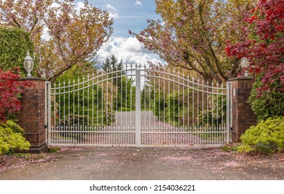 Iron front gate of a luxury home. Wrought iron white gate and brick pillar. Nobody, street photo, selective focus