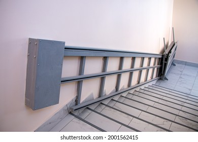 iron gray electric wheelchair lift with a ramp and a chain mechanism for lifting along the stairs, for lifting wheelchairs to the floor above.