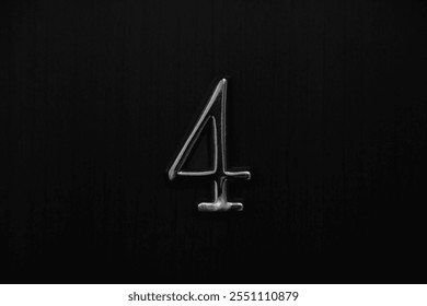 iron House number 4 on a brown wooden front door. flat room apartment in hotel metal digit four on grey wood wall fence with black door. screwed down with a screw. in front view.