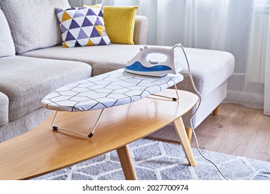 Iron for ironing on small tabletop ironing board in cozy and living room, small apartments
