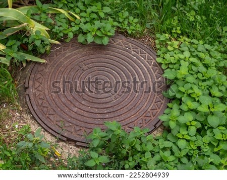 Iron manhole of the city sewer. A rusty manhole on a concrete base closes the entrance to the sewer lines. City sewer system.