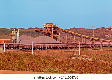 Iron ore stockpile and transfer conveyor with fully loaded rail wagons in Western Cape, South Africa - Shutterstock ID 1411804766
