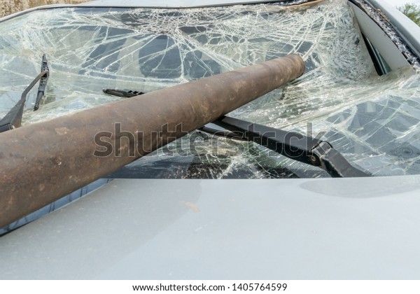 The iron pipe lies on the broken windshield of the\
car. Damage to the windshield with the power of an iron pipe, glass\
in cracks