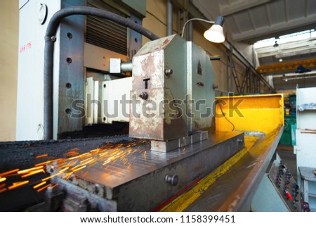Iron rectangular parts on a flat grinding machine are treated with an abrasive wheel, wide-angle photo.