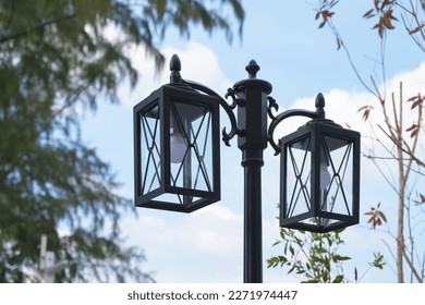 Iron Rectangular street lamp with a transparent glass shade against a clear blue sky. Street lighting, urban illumination, improvement of the city. - Shutterstock ID 2271974447
