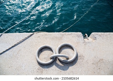 Iron rings on the pier where yachts are anchored in the marina. Two rings and ropes with which the boats are tied to the pier with ropes. The rings are in selective focus.