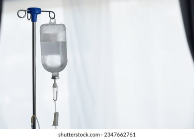 An iron stand to hang saline bottle high to deliver saline via catheter to an intravenous patient lying on patient bed. Medical concept in which doctor gives saline solution to patient through vein - Powered by Shutterstock