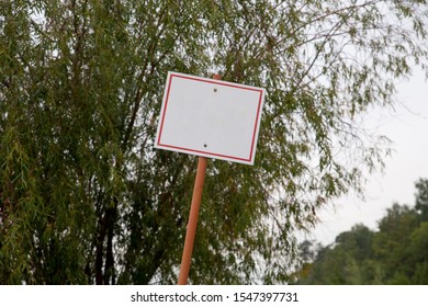 Iron White With Red Edge Rectangular Blank Road Sign On Trees Background. Mockup