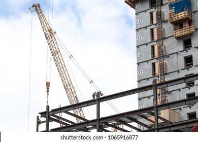 Iron Workers On I Beam Framing For A Modern Sky Scraper, With A Crane And Concrete Elevator Shaft In The Background