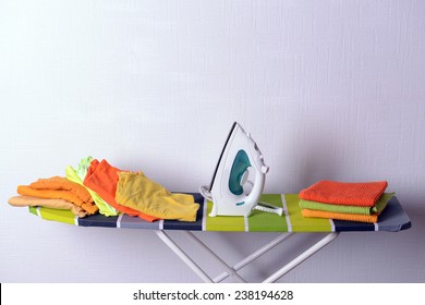 Ironing board with laundry on light background - Powered by Shutterstock