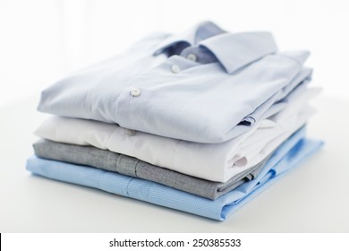 Ironing, Laundry, Clothes, Housekeeping And Objects Concept - Close Up Of Ironed And Folded Shirts On Table At Home