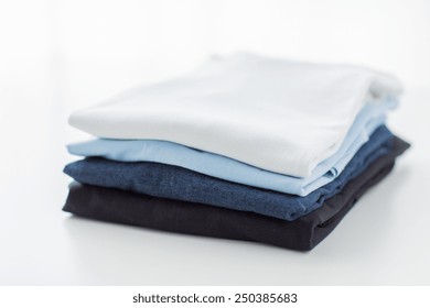 ironing, laundry, clothes, housekeeping and objects concept - close up of ironed and folded t-shirts on table at home